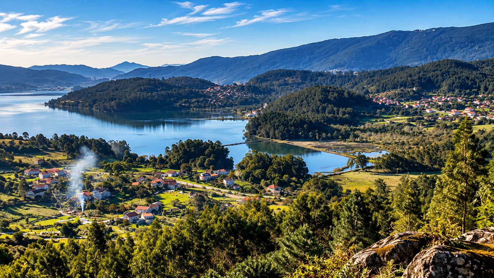 Panorámica de una ensenada entre montes arbolados, campos y viviendas